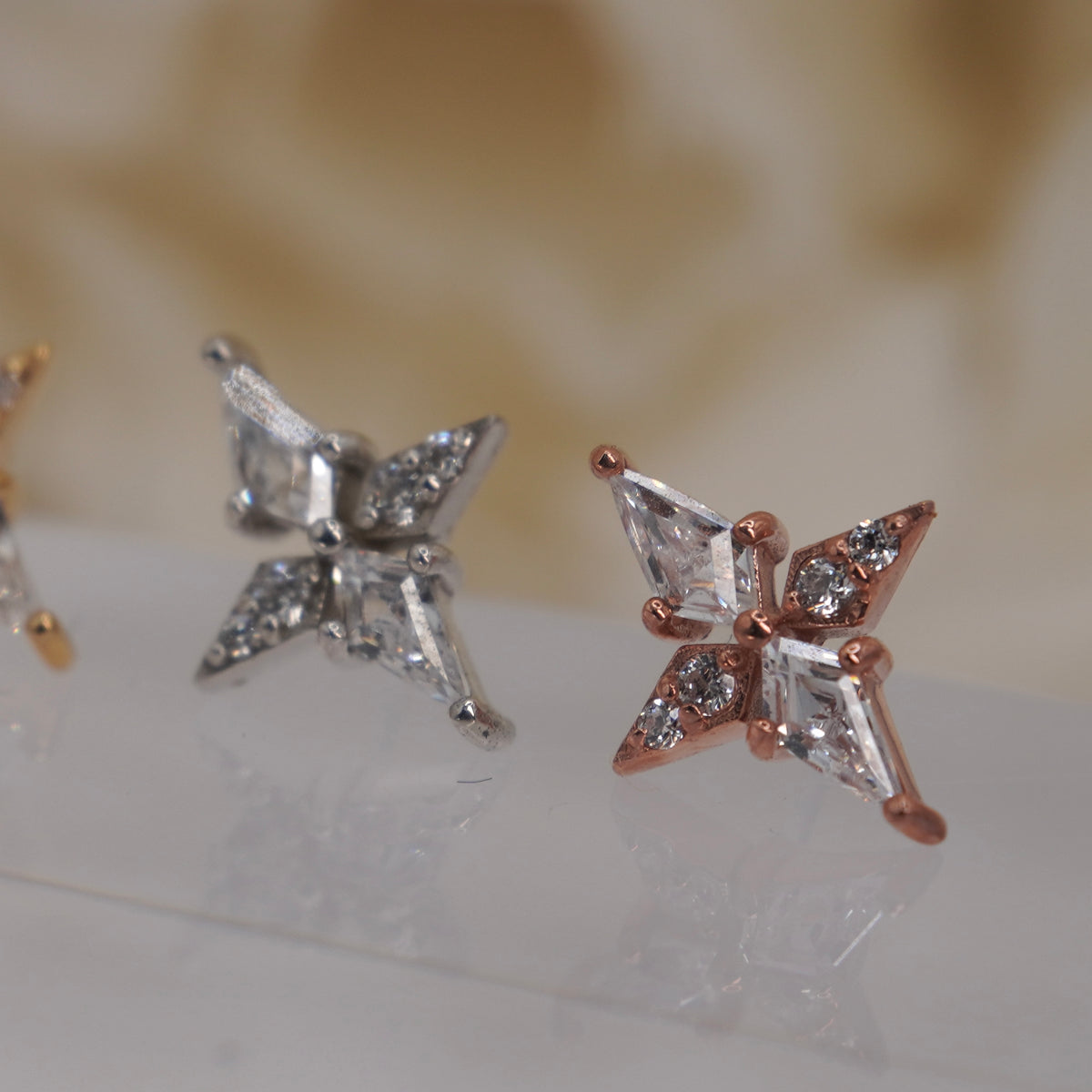 Angled view of Buddha Jewelry’s “Feeling Myself” in 14k yellow, white, and rose gold, showing its sharp lines, polished finish, and sparkling crystal details.