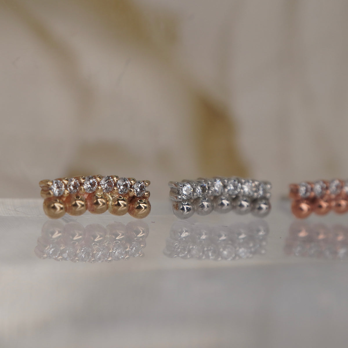 Angled view of Buddha Jewelry’s “Prophesy” in 14k yellow, white, and rose gold, showing the dimensional beadwork and crystal-lined silhouette.
