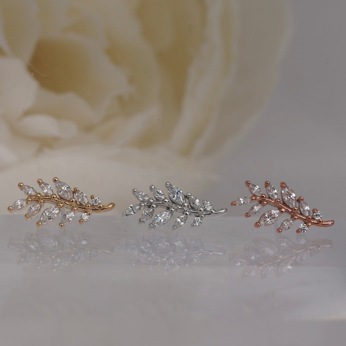 Front view of Buddha Jewelry’s “Botaniste” in 14k yellow, white, and rose gold, featuring a winding branch design with shimmering crystals and marquise-shaped accents.