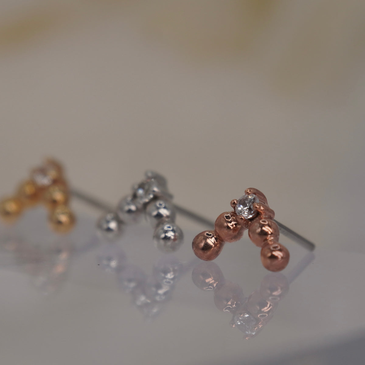 Angled view of Buddha Jewelry’s “Voodoo” in 14k yellow, white, and rose gold, showing the dimensional gold beadwork and crystal drop.
