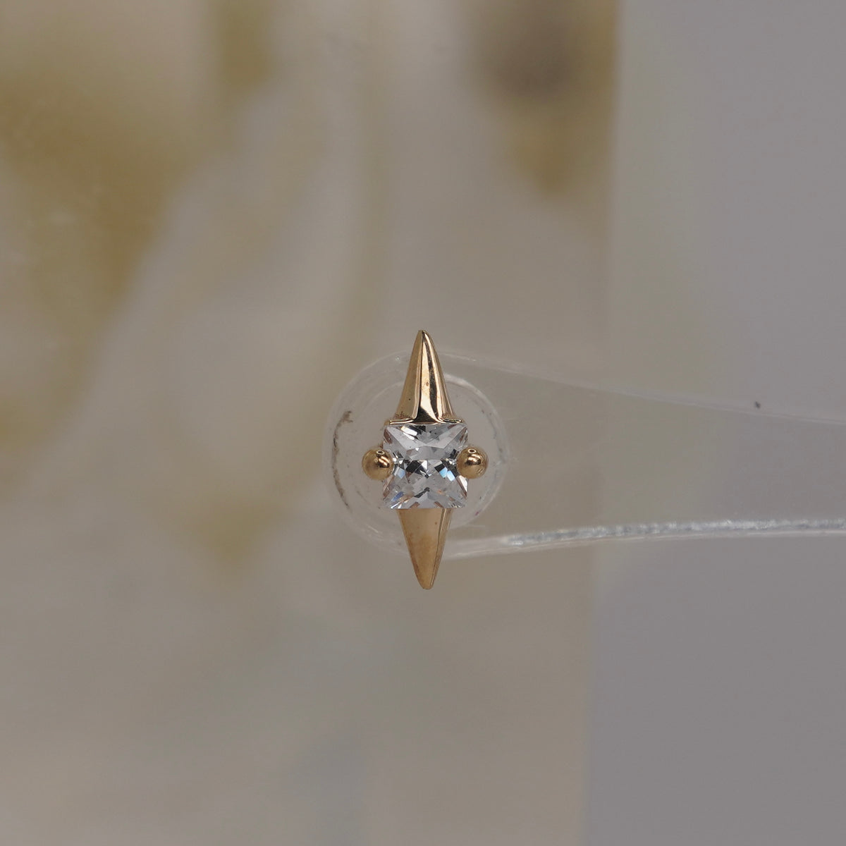 Front view of Buddha Jewelry’s “Elemental” in 14k yellow gold, featuring a central square-cut crystal between pointed gold tips.