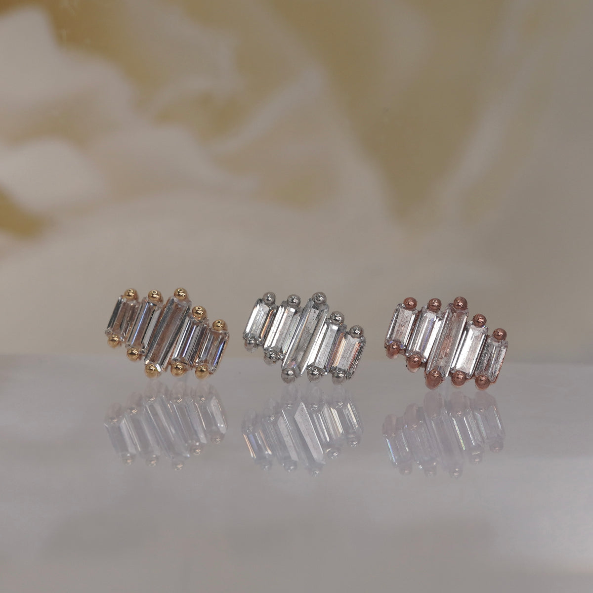 Front view of Buddha Jewelry’s “Evolution” in 14k yellow, white, and rose gold, featuring a graduated row of elongated crystals.