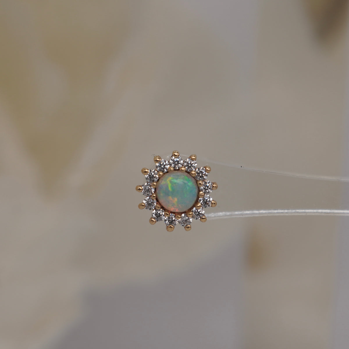 Front view of Buddha Jewelry’s “Delphine” in 14k yellow gold, featuring a glowing opal framed by sparkling crystal petals.