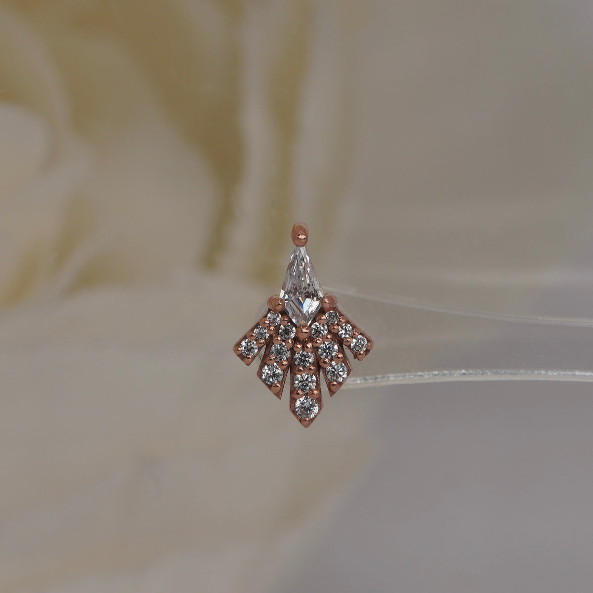 Front view of Buddha Jewelry’s “Savor” in 14k rose gold, featuring a kite-shaped crystal and a spreading fan of sparkling stones.