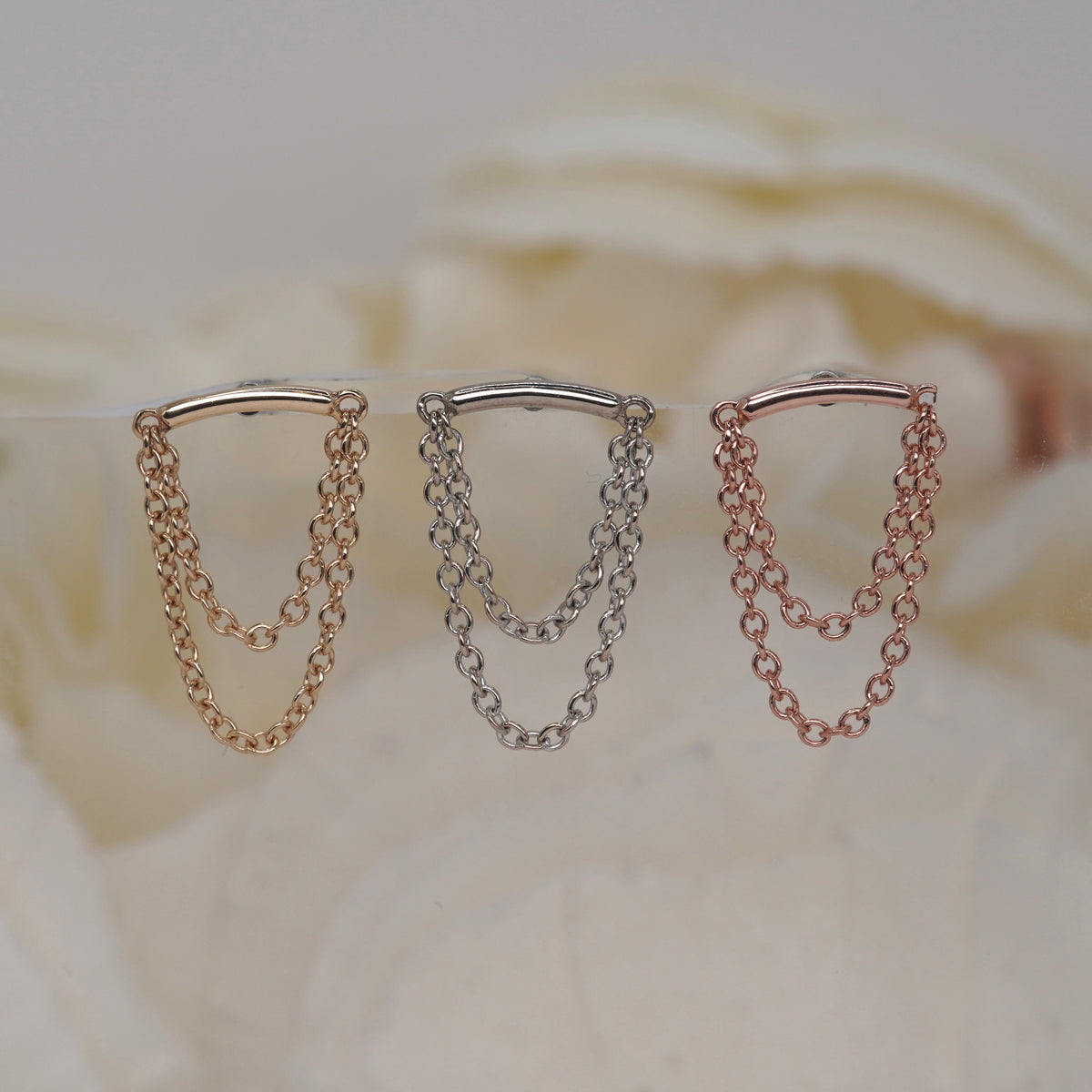 Swagger Hidden Helix 16g leroi with layered chain drops in yellow gold, white gold, and rose gold, displayed against a soft cream background.