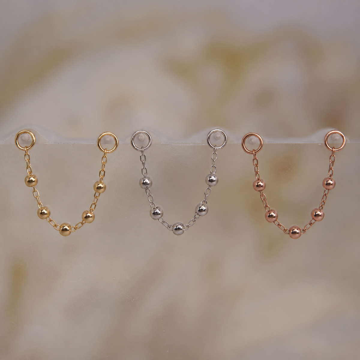 Front view of Buddha Jewelry’s “Cressida” chains in 14k yellow, white, and rose gold, each featuring three subtly textured beads spaced along a fine chain.
