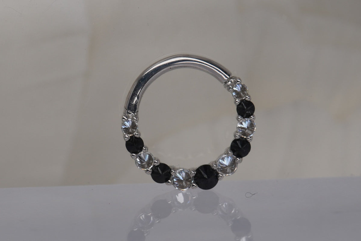 Front view of Buddha Jewelry’s “Eclipse” clicker in 14k white gold, featuring alternating round black spinel stones and sparkling crystals along the ring.