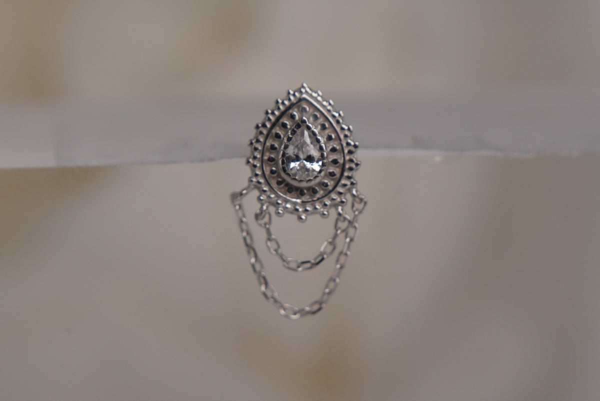 Front view of Buddha Jewelry’s “Deity” in 14k white gold, featuring a luminous center crystal framed by ornate goldwork with delicate chains draped below.