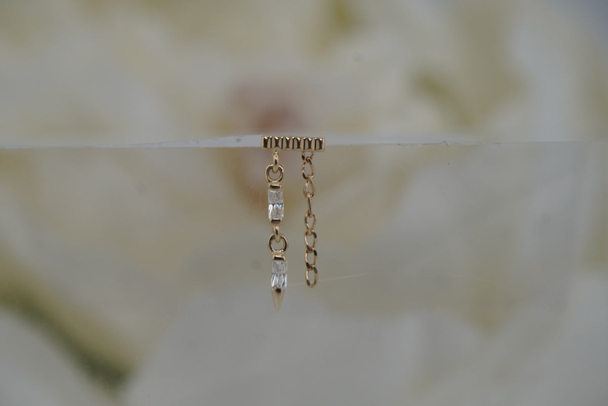 Front view of Buddha Jewelry’s “Double Vision” in 14k yellow gold, featuring a ribbed top bar, vertical crystal row, pointed spike, and delicate side chain.