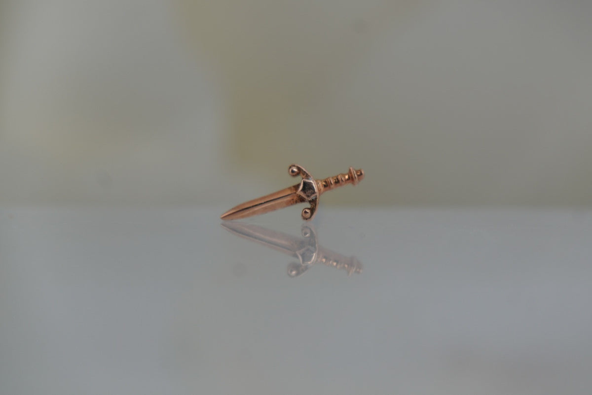Front view of Buddha Jewelry’s “Blade” in 14k rose gold, featuring a sleek, elongated sword silhouette with a polished finish.