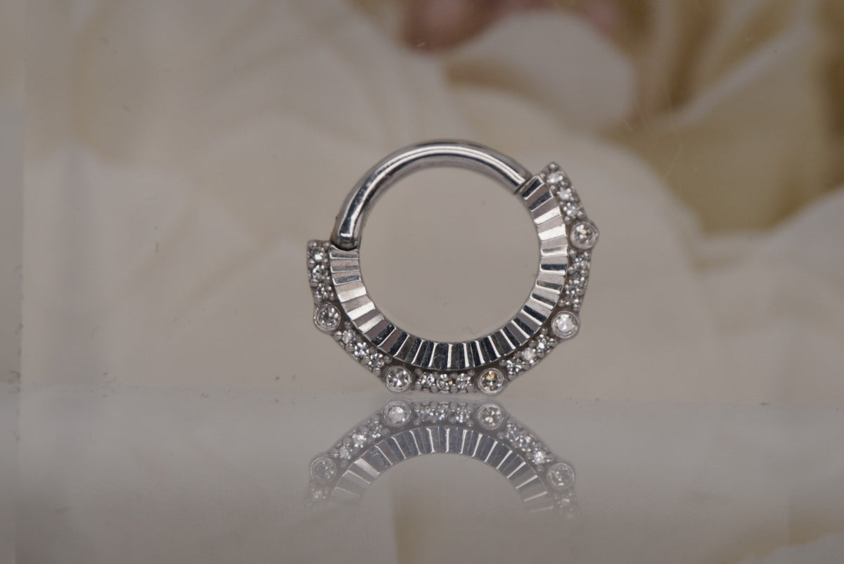 Front view of the white gold Awaken clicker with genuine diamonds and sunburst-like texture.