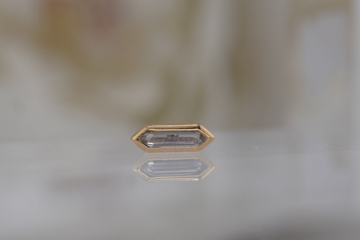 Front view of the elongated 14k yellow gold design with a white baguette-cut crystal.