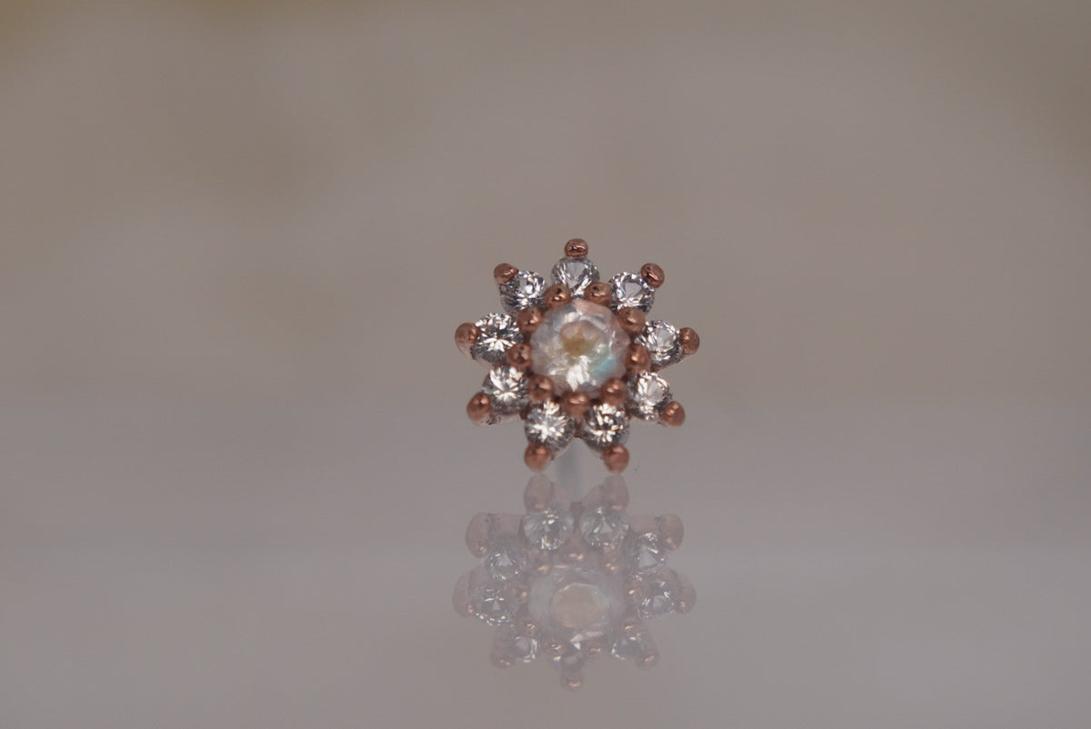 Front view of Buddha Jewelry’s “Eloise” in 14k rose gold, featuring a glowing rainbow moonstone center framed by delicate white sapphire petals.