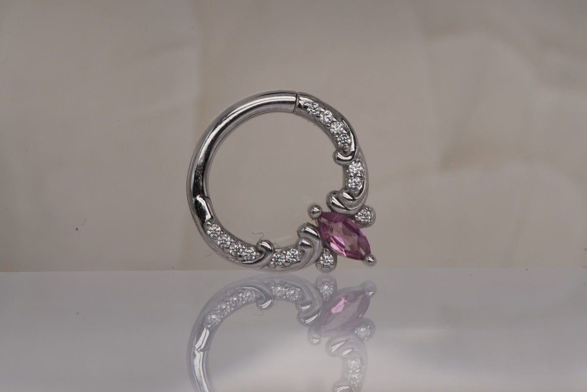 Front view of Buddha Jewelry’s “Coterie” clicker in 14k white gold, featuring a marquise-cut pink tourmaline accented by delicate crystals and ornate scrollwork.