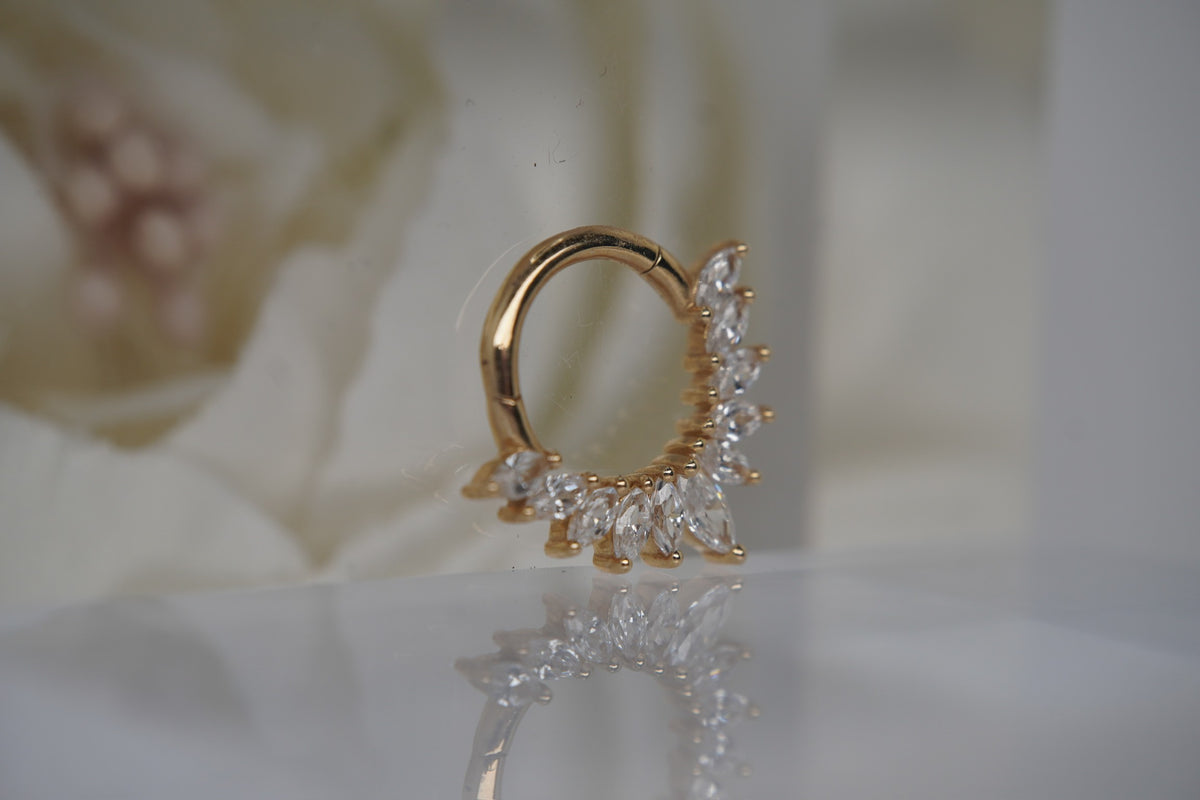 Angled view showing the clicker’s crystal settings and gold finish.