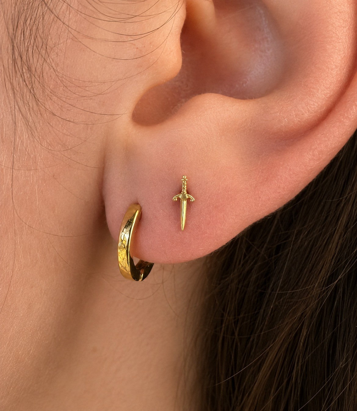 Buddha Jewelry’s “Blade” worn in a piercing, showing its elongated sword shape and sharp, polished details.