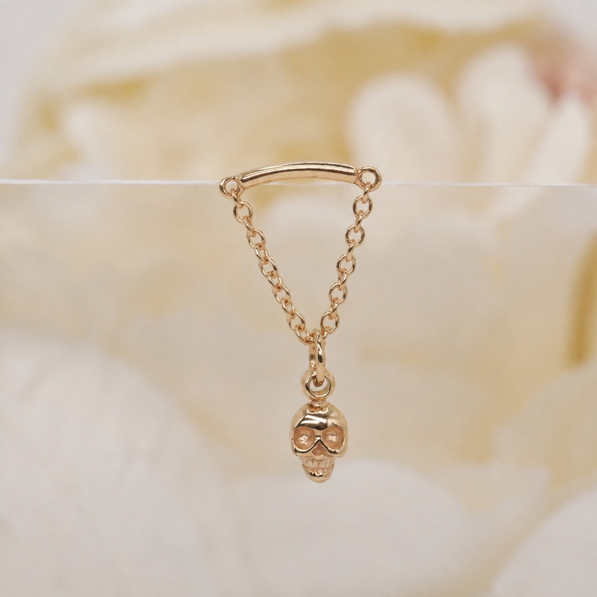 Glide Spooky Hidden Helix 16g yellow gold against a soft white rose background.