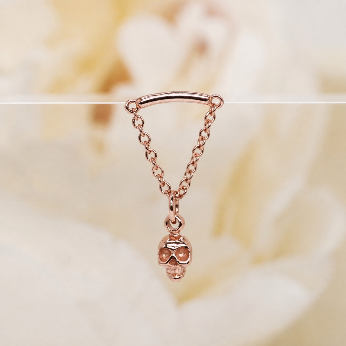 Glide Spooky Hidden Helix 16g rose gold against a soft white rose background.