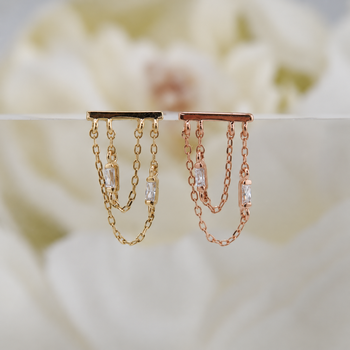 Front view of Attention Everyone threadless ends in 14k yellow and rose gold with two baguette CZ chain drops.
