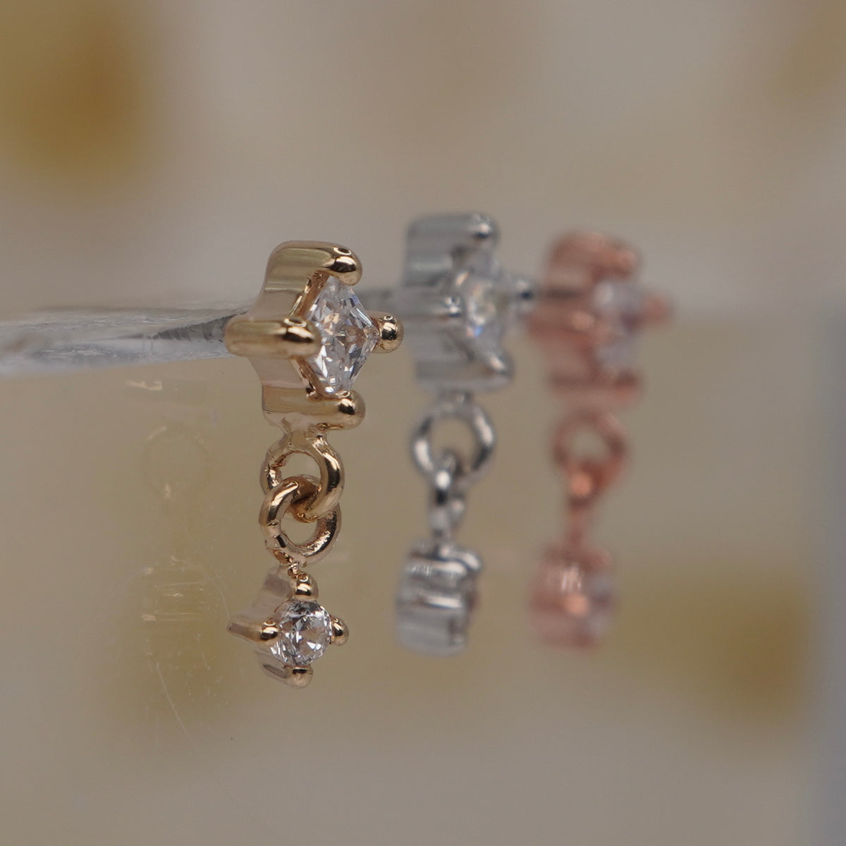 Buddha Jewelry 14k Gold fun and games small princess cut white crystal in a prong setting connected to a dangling small white crystal in a prong setting in Yellow Gold White Gold Rose Gold threadless group side view showing detail