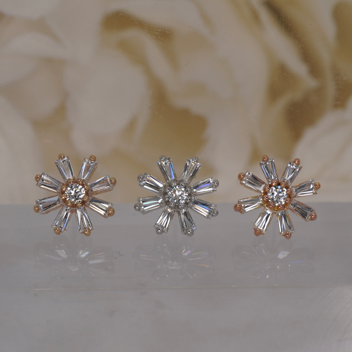 Front view of Buddha Jewelry’s “Deliah” in 14k yellow, white, and rose gold, featuring a central crystal surrounded by tapered baguette crystals in a floral starburst.