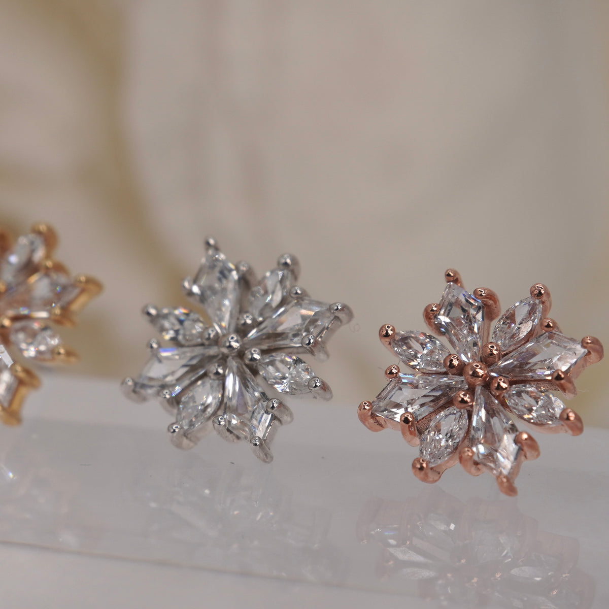 Angled view of Buddha Jewelry’s “Hauteness” in 14k yellow, white, and rose gold, showing the layered marquise crystals and dimensional starburst silhouette.