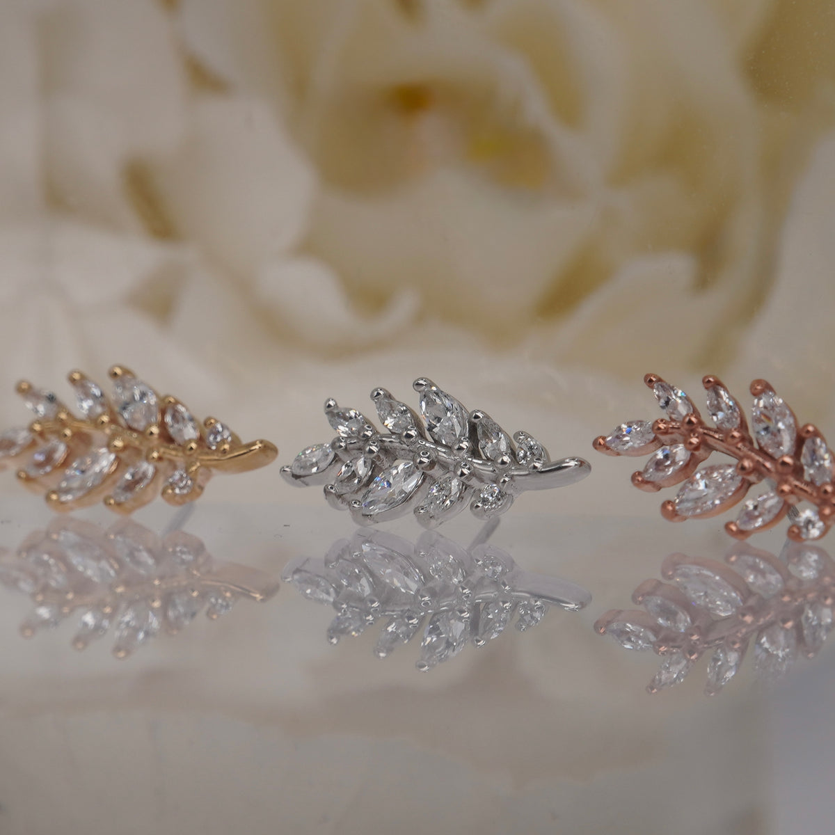 Angled view of Buddha Jewelry’s “Botaniste” in 14k yellow, white, and rose gold, showing its curved branch silhouette and dimensional crystal details.