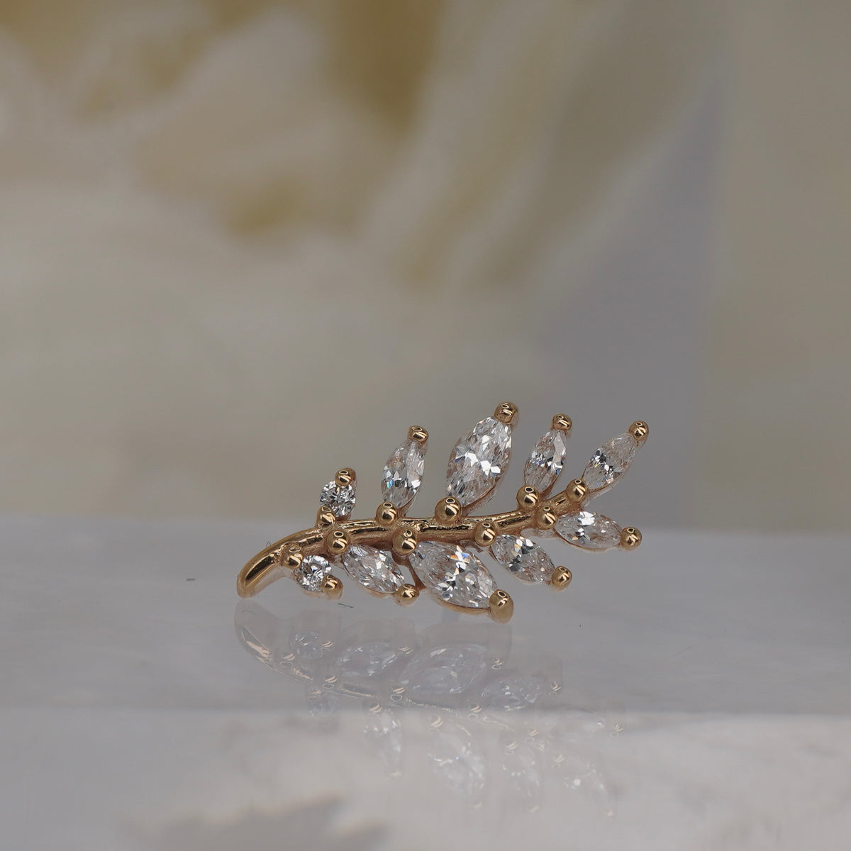 Front view of Buddha Jewelry’s “Botaniste” in 14k yellow gold, featuring an elongated crystal branch with marquise-shaped accents.