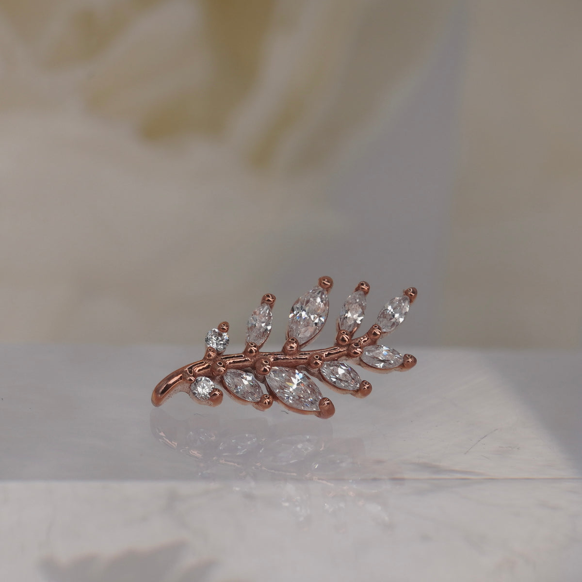 Front view of Buddha Jewelry’s “Botaniste” in 14k rose gold, featuring an elongated crystal branch with marquise-shaped accents.