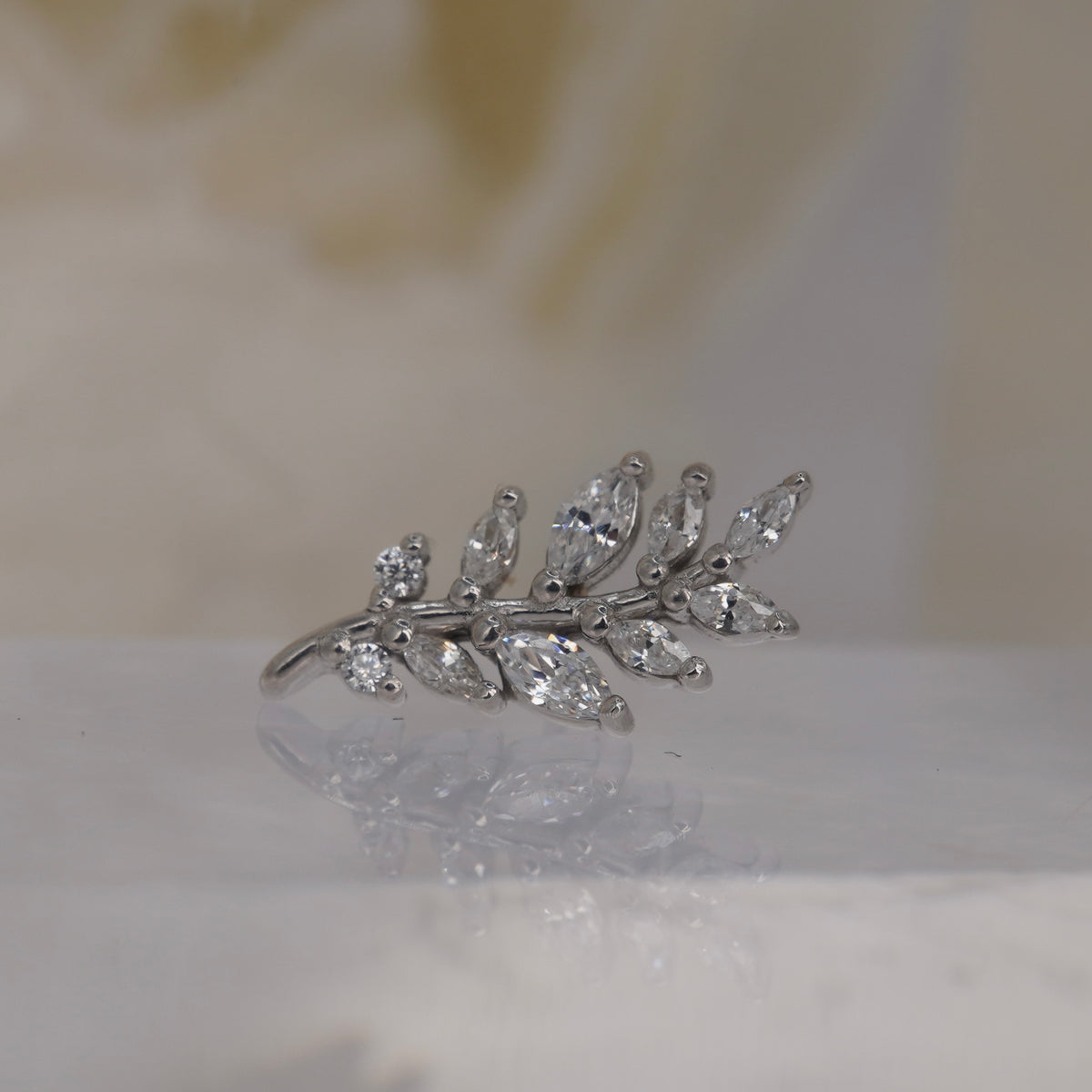Front view of Buddha Jewelry’s “Botaniste” in 14k white gold, featuring an elongated crystal branch with marquise-shaped accents.