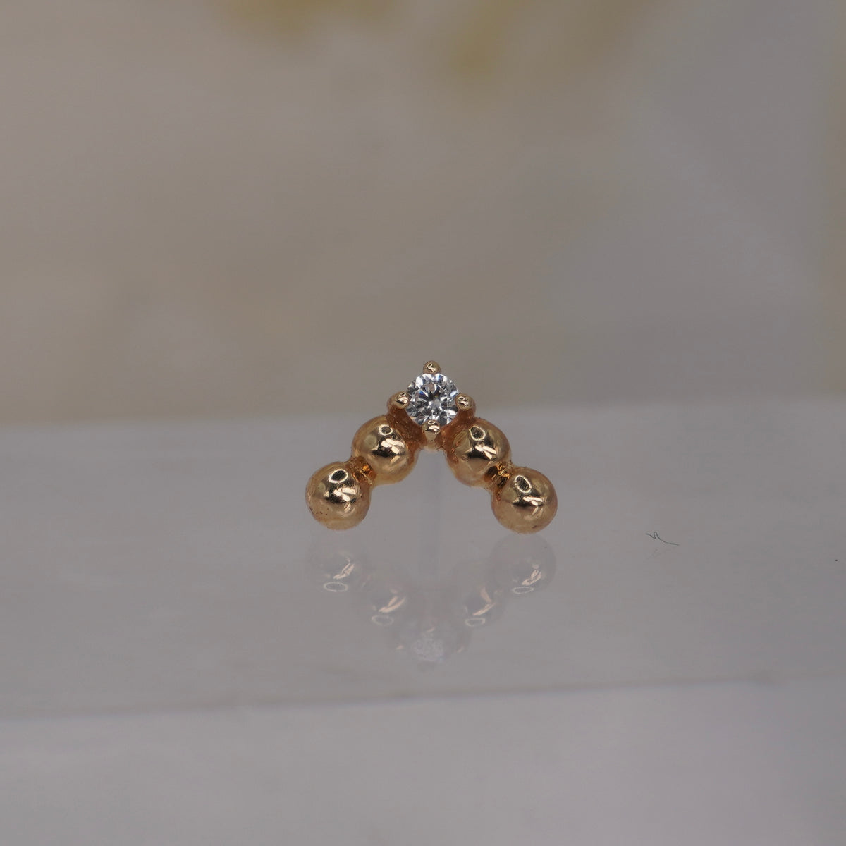 Front view of Buddha Jewelry’s “Voodoo” in 14k yellow gold, featuring a structured V of polished gold beads above a single crystal drop.