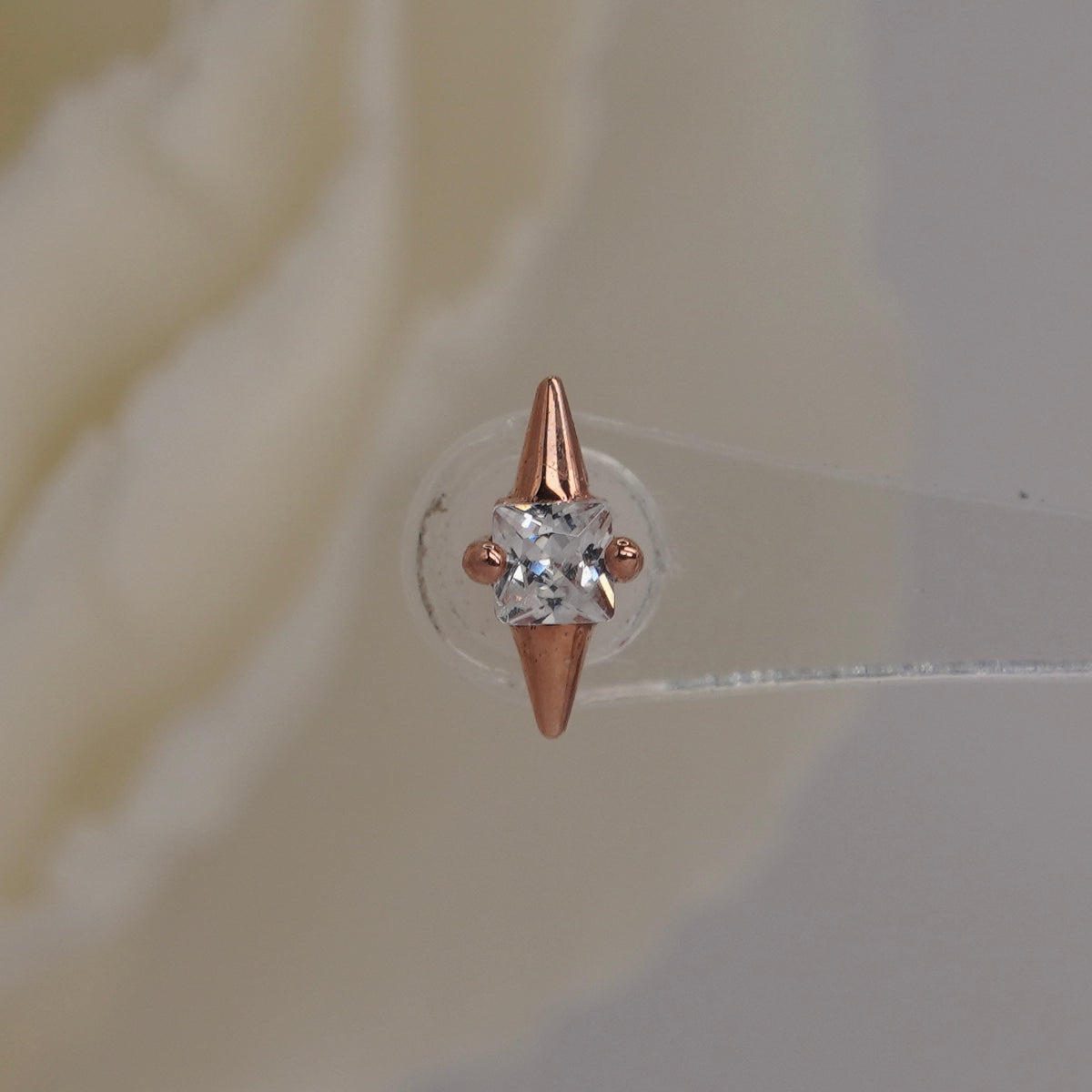 Front view of Buddha Jewelry’s “Elemental” in 14k rose gold, featuring a central square-cut crystal between pointed gold tips.
