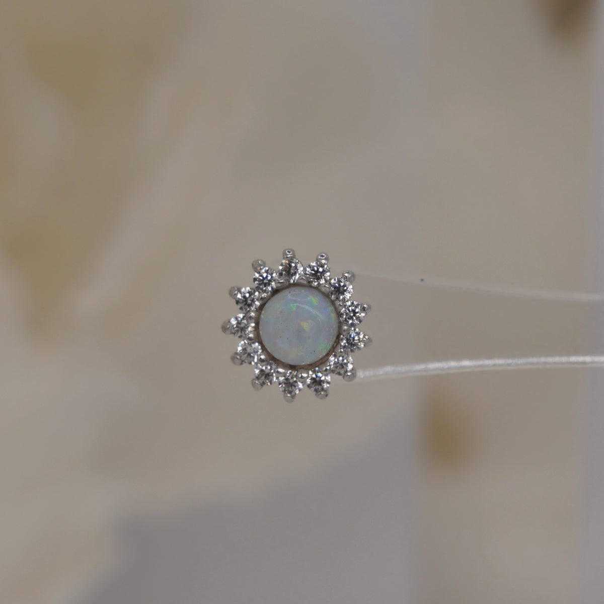 Front view of Buddha Jewelry’s “Delphine” in 14k white gold, featuring a glowing opal framed by sparkling crystal petals.