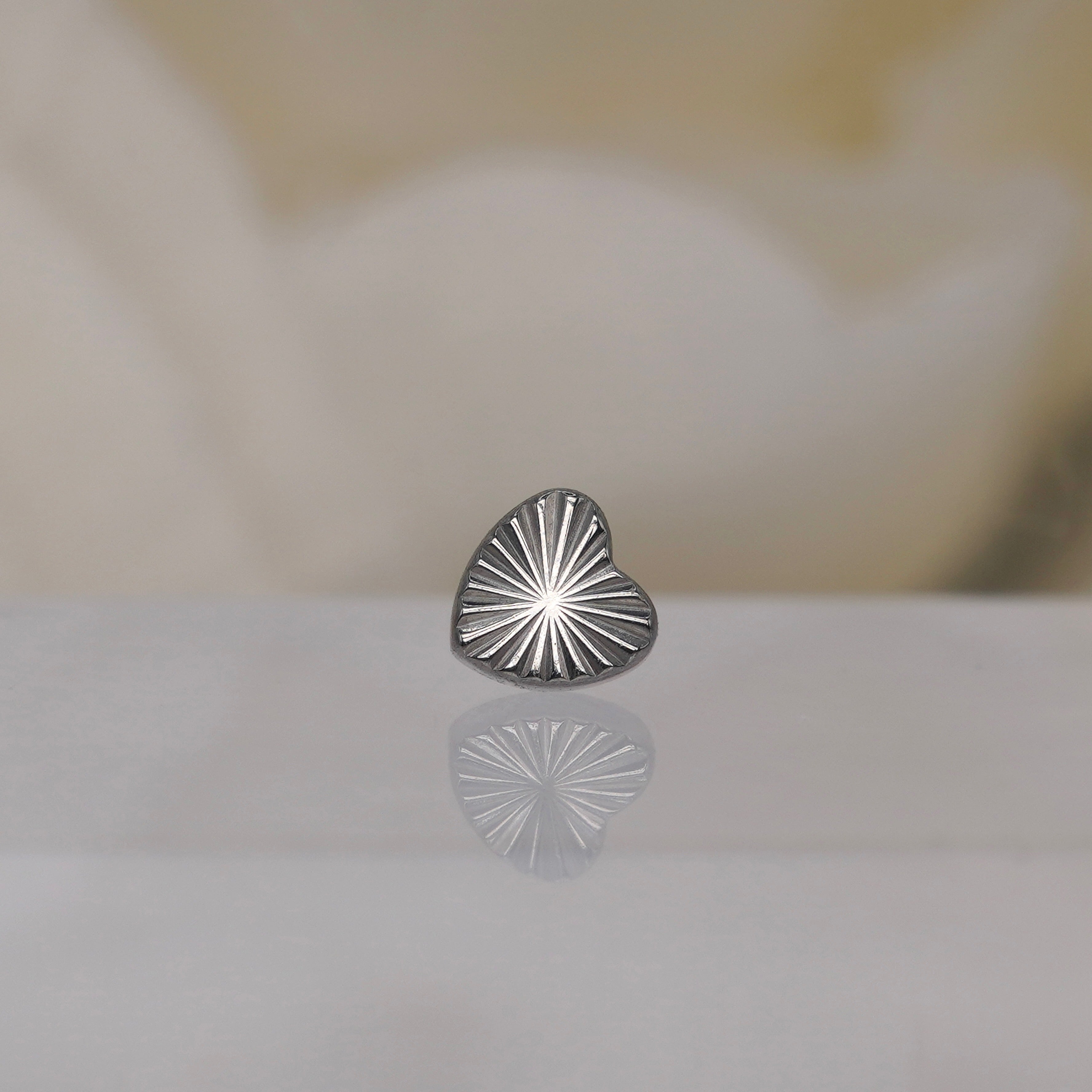 Threadless Implant Grade Titanium Laser Heart by Junipurr with a soft, blurred cream background.