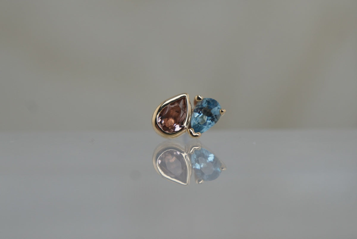 Front view of Buddha Jewelry’s “Era” in 14k yellow gold, featuring pear-cut pink tourmaline paired with London Blue Topaz.
