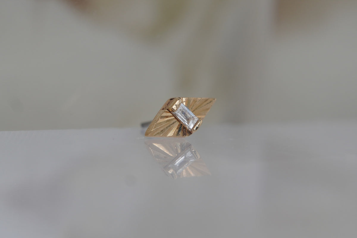 Front view of the elongated 14k yellow gold diamond-shaped design with a genuine baguette white diamond.