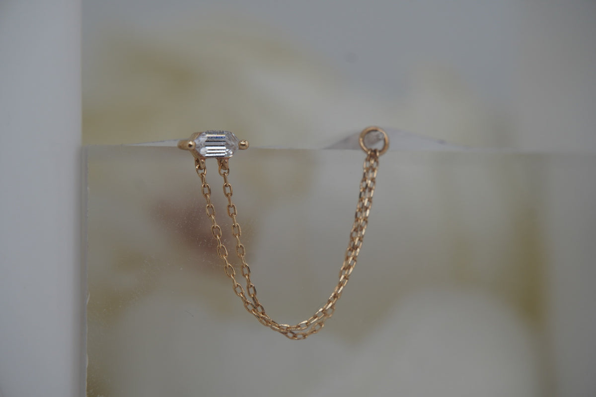 Angled view showing the crystal setting and elongated gold chain.