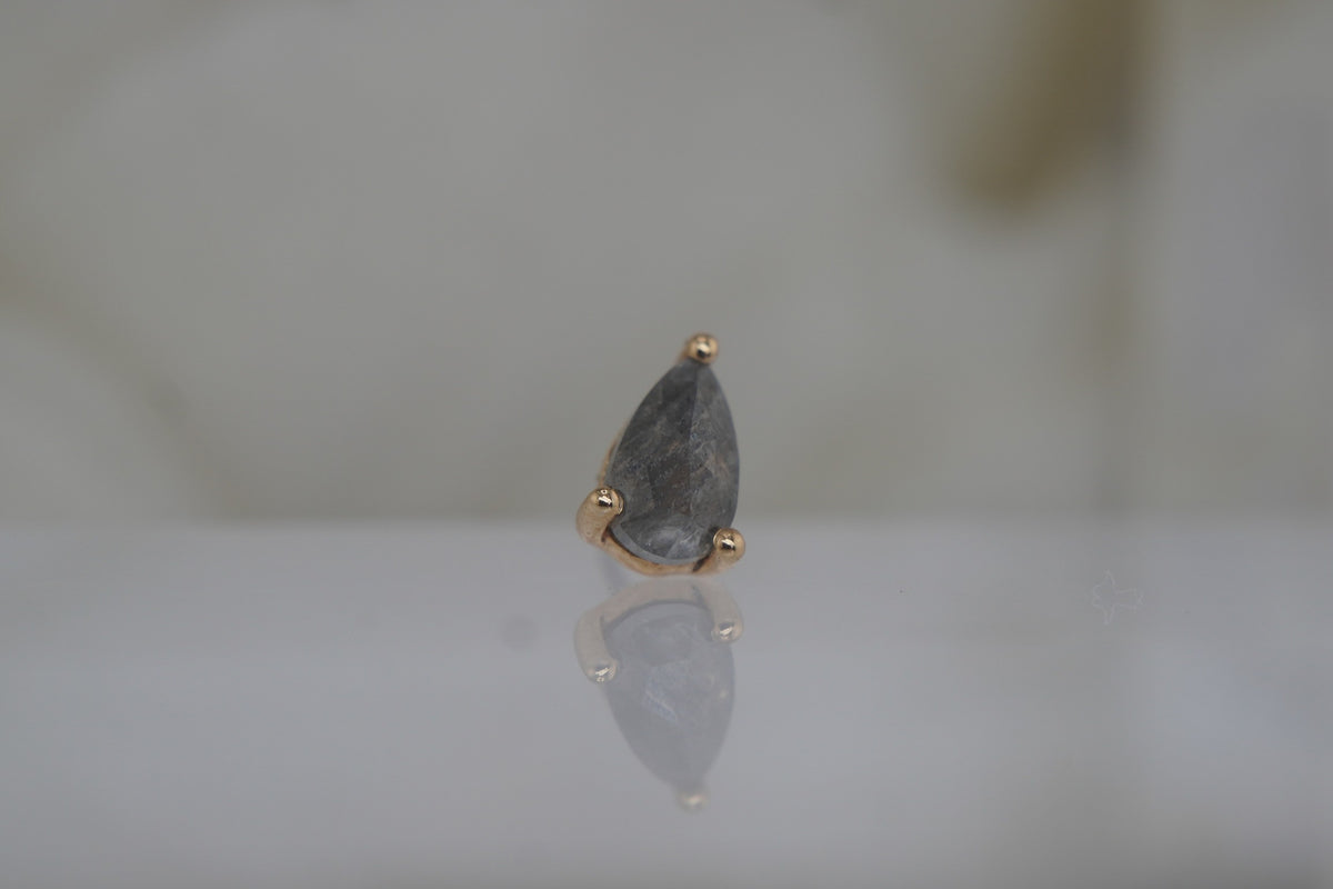 Angled view showing the grey diamond and gold setting.