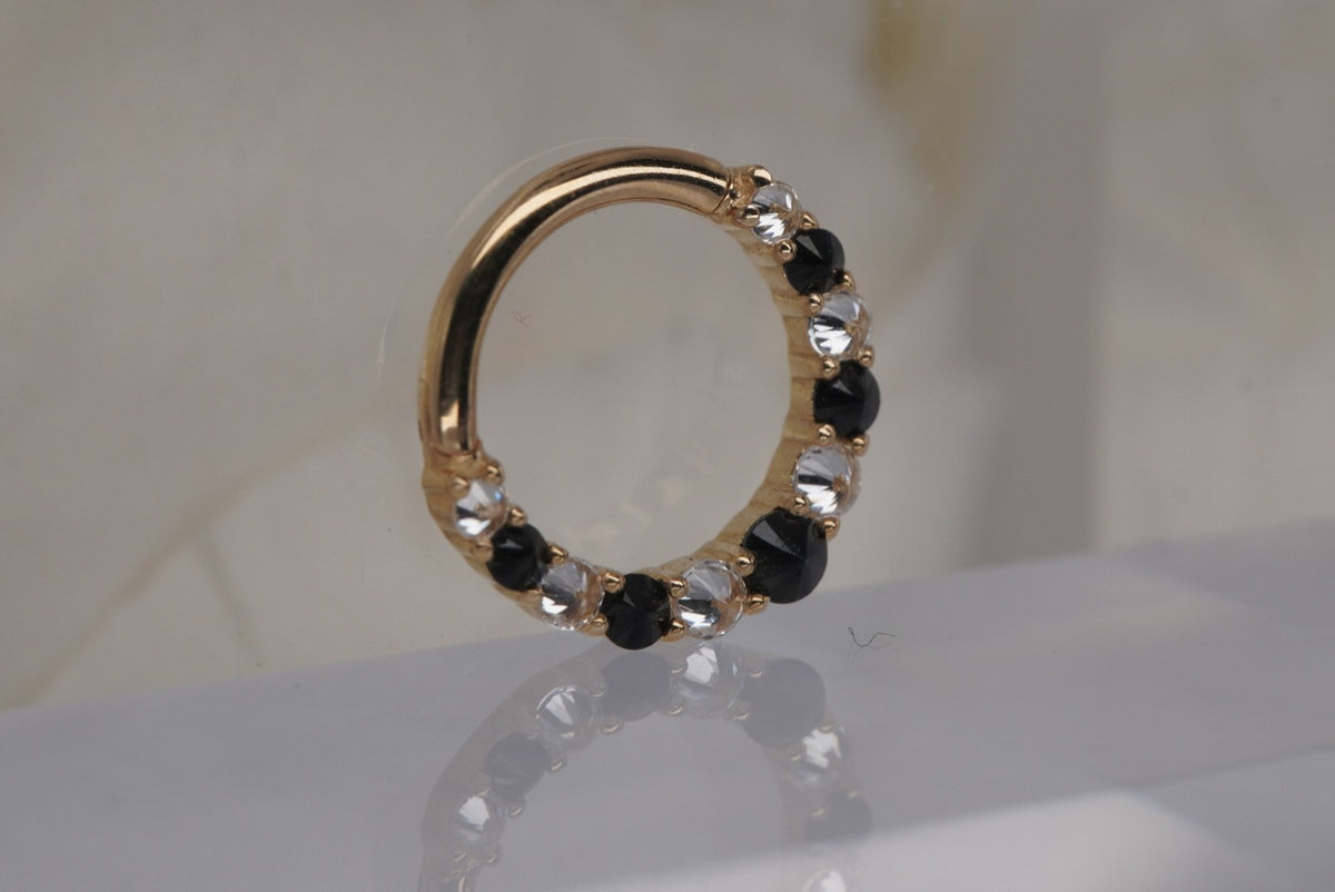 Angled Photo of Buddha Jewelry 14k "Eclipse" clicker in 16g 5/16" OR 3/8" with White Crystals and Black Spinel in yellow gold showing reverse set gems septum daith piercing