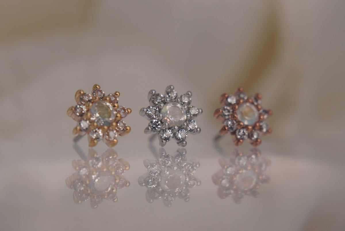 Angled view of Buddha Jewelry’s “Eloise” in 14k yellow, white, and rose gold, highlighting the moonstones’ iridescent glow and shimmering white sapphire petals.