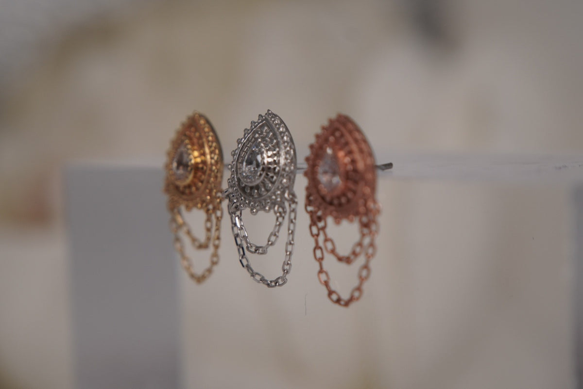 Angled view of Buddha Jewelry’s “Deity” in 14k yellow, white, and rose gold, highlighting the intricate goldwork, sparkling center crystals, and draped chains.