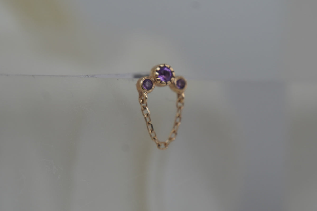 Angled view showing the amethyst settings and delicate gold chain.