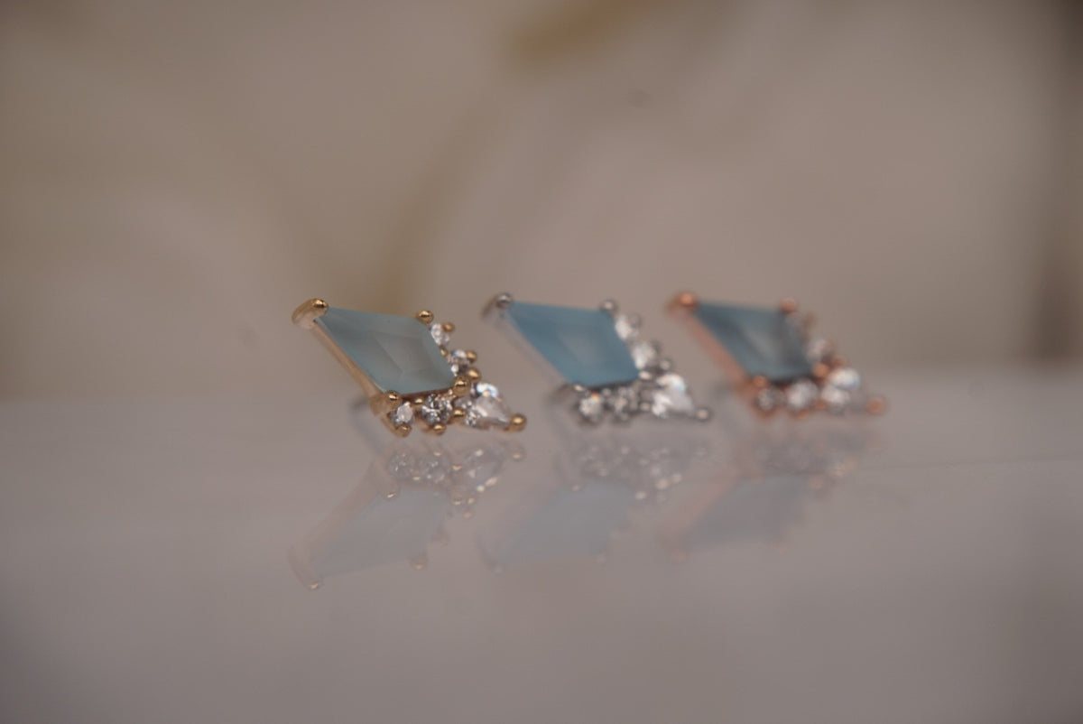 Angled view of all three Afterglow gold finishes, showing the blue topaz and sparkling accents.