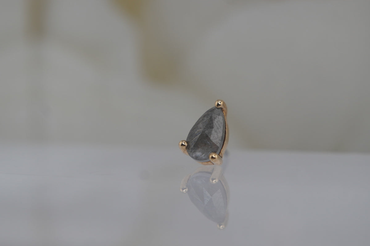 Angled front view of the genuine pear-shaped grey diamond set in 14k yellow gold.