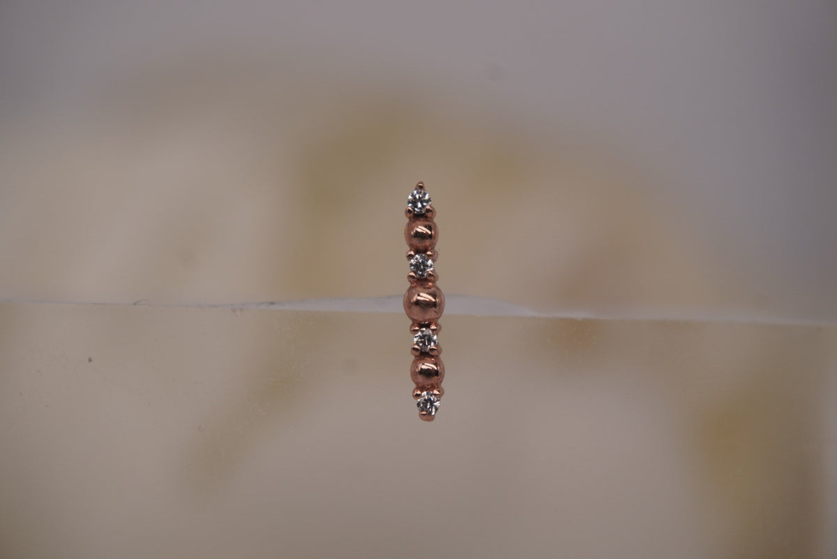 Front view of Buddha Jewelry’s “Chance” in 14k rose gold, featuring alternating polished beads and shimmering crystals in a slim vertical arrangement.