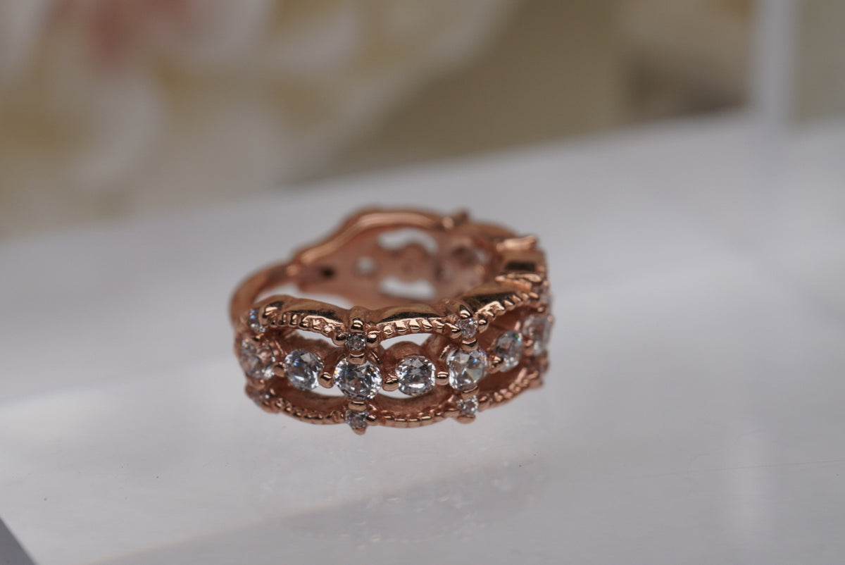 Photo of "Chaaya" Clicker in 16g 3/8" Rose Gold with White Crystals, laying down angled