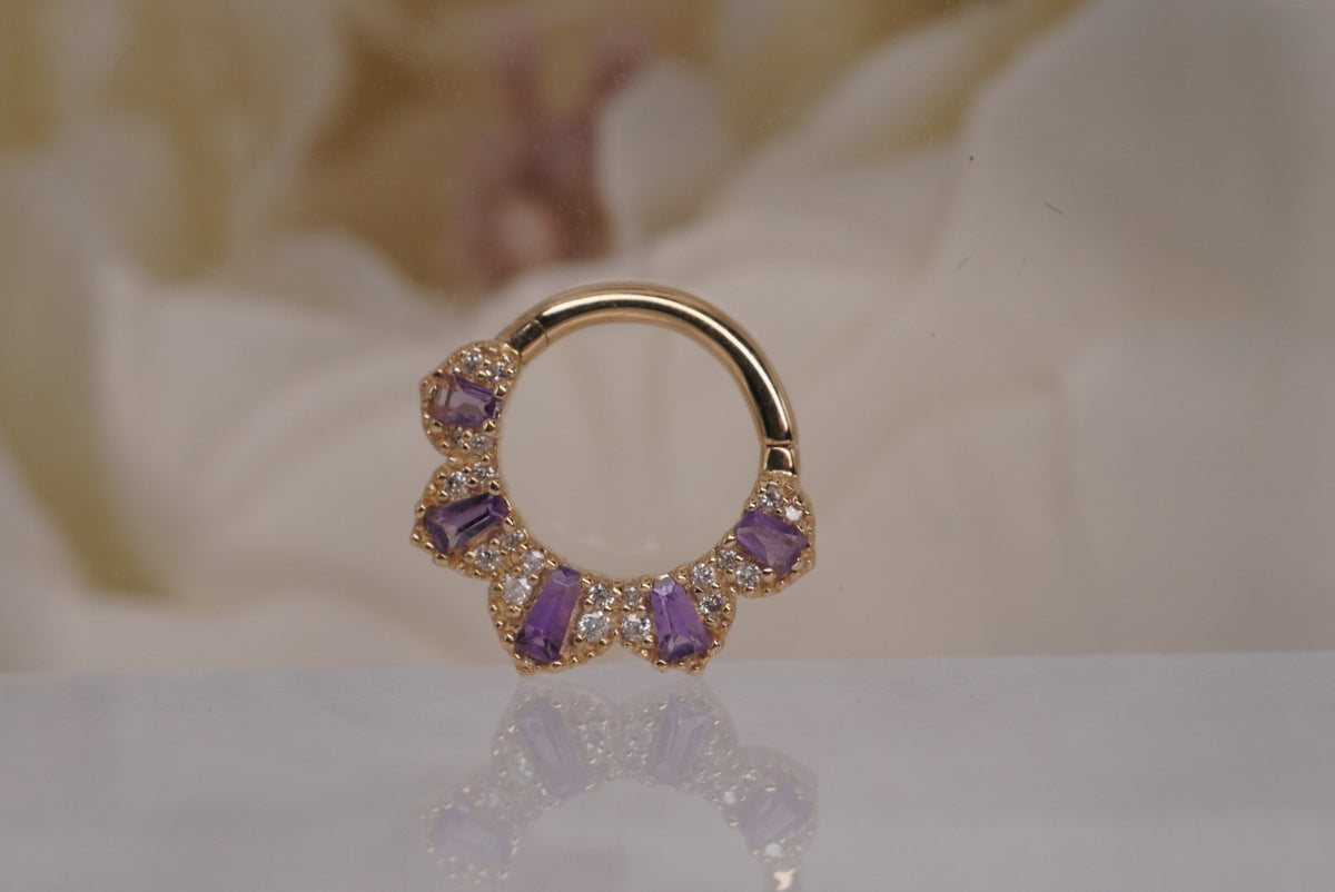 Front view of Buddha Jewelry’s “Gilty Pleasure” clicker in 14k yellow gold, featuring a curved fan of amethyst baguettes accented with genuine white diamonds.