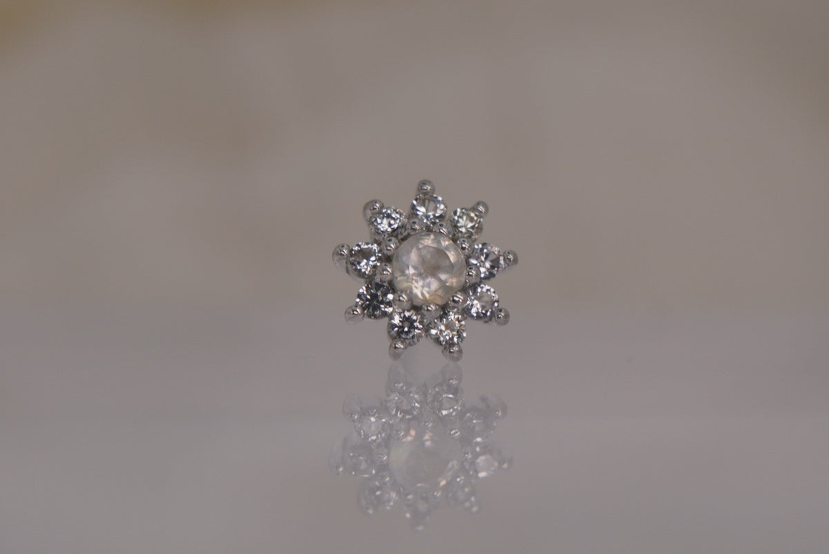 Front view of Buddha Jewelry’s “Eloise” in 14k white gold, featuring a glowing rainbow moonstone center framed by delicate white sapphire petals.