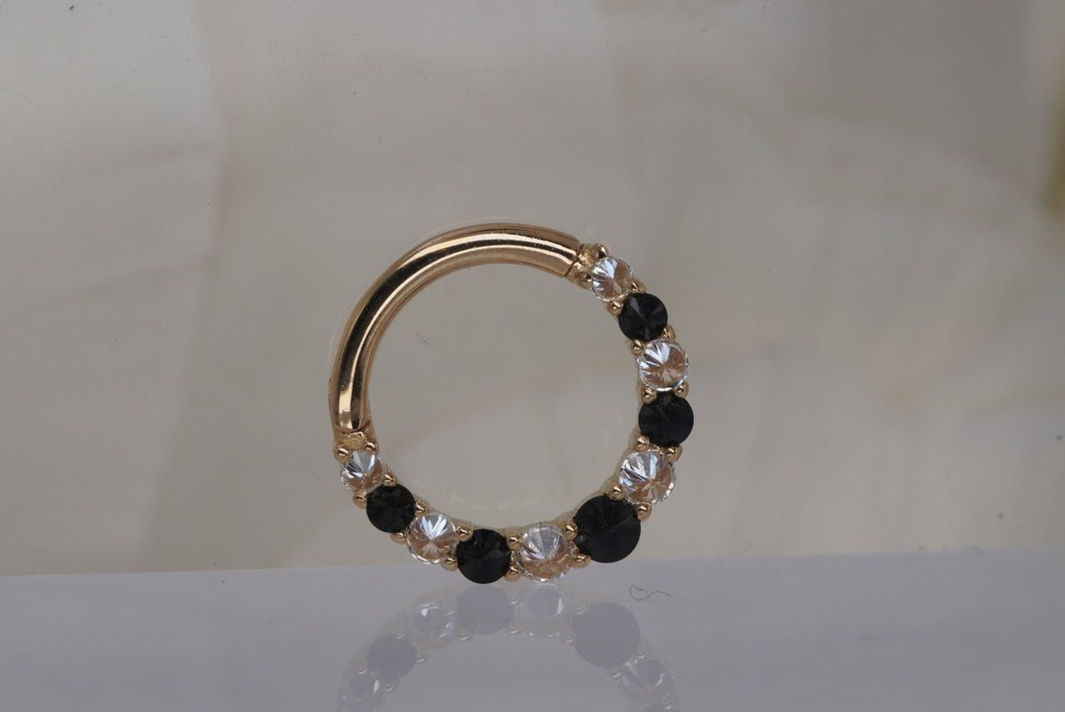 Front view of Buddha Jewelry’s “Eclipse” clicker in 14k yellow gold, featuring alternating round black spinel stones and sparkling crystals along the ring.