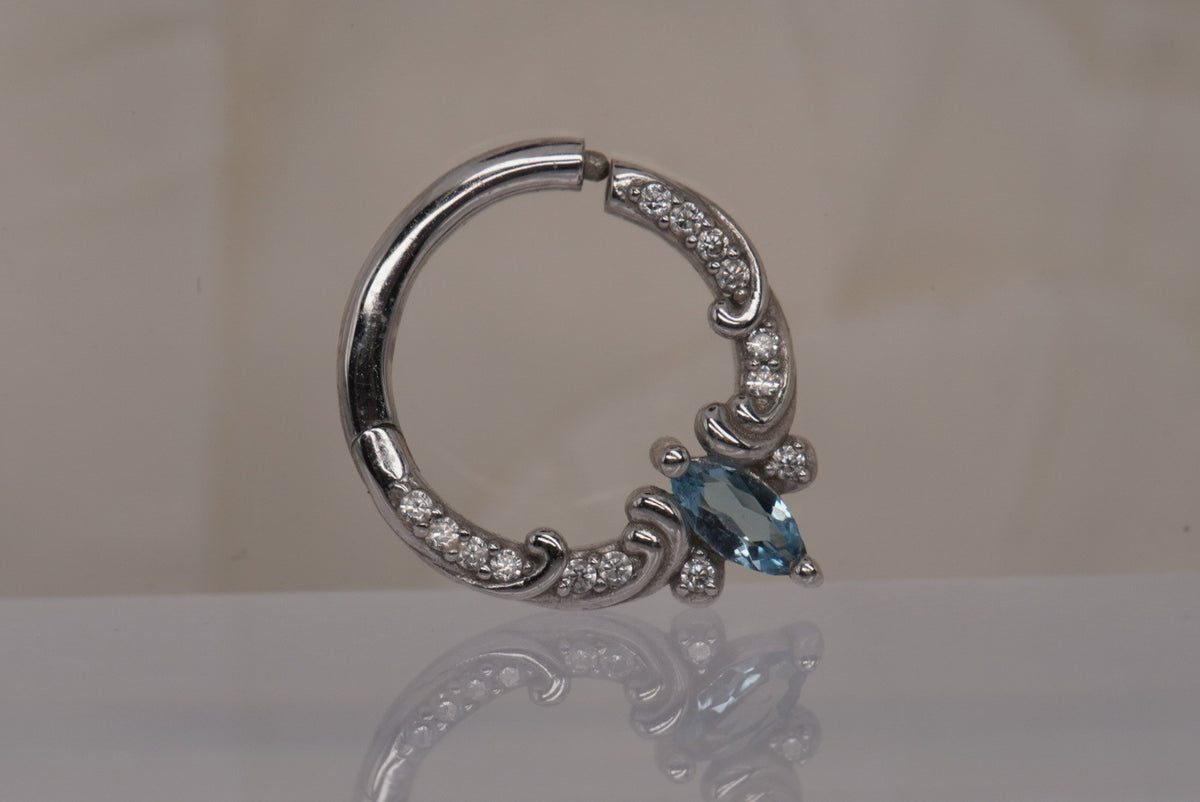 Front view of Buddha Jewelry’s “Coterie” clicker in 14k white gold, featuring a marquise-cut London Blue Topaz accented by a delicate row of crystals.